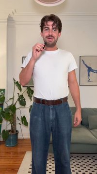 Kék farmernadrág laza fazonnal és magas derékkal, egy testhezálló fehér rövidujjú pólóval és egy barna bőr övvel párosítva.