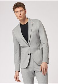 Helles graues Blazer mit taillierter Passform, zwei Knöpfen, Reverskragen und schmaler Silhouette; verfügt über zwei vordere Taschen und eine dezente Textur.