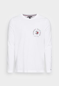 T-shirt bianco a maniche lunghe in cotone, con una stampa del logo circolare in nero, rosso e blu sul petto, dal design con scollo rotondo.