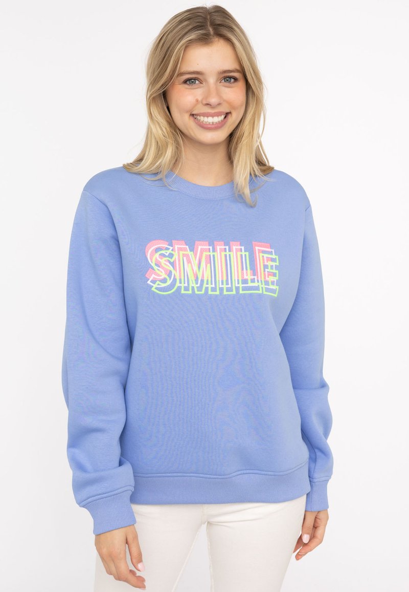Hellblaues Sweatshirt mit gerippten Bündchen und Saum. Verziert mit dem Wort "SMILE" in bunten, fetten Lettern über die Brust. Weicher Stoff.