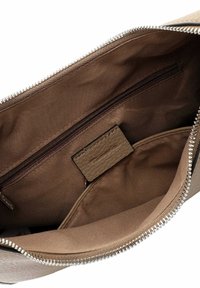 Innenraum einer braunen, stoffgefütterten Tasche mit einem silbernen Reißverschluss, einer inneren Reißverschlusstasche und einem kleinen eingenähten Lederetikett.