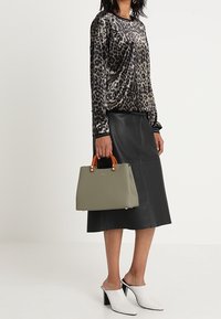 Kožená sukně, svetr s leopardím vzorem a světle šedá kabelka s hnědými uchy. Bílá obuv se širokým podpatkem dotváří celkový vzhled.