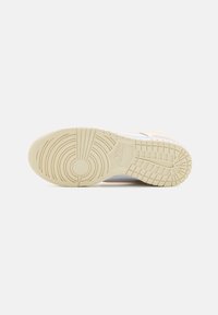 Weiße Sneaker-Sohle mit einem strukturierten Muster, das ein kreisförmiges Emblem und gerippte Traktionselemente aufweist. Cremig-beiges Gummi-Material.