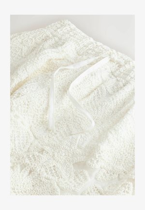 Balta tamborēšanas auduma ar reljefa rakstiem un aukliņas aizdari. Mīksts, viegls materiāls ar sarežģītām detaļām.