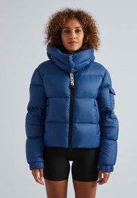 Blauwe pufferjack met een hoge kraag, ritssluiting, binnenzakken en elastische manchetten. Glad oppervlak met een glanzende afwerking en logo-label.