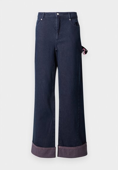 Široke traperice iz temno modrega bombaža z urejenim robom, ki imajo roza oznako na strani in klasičen pet-žepni dizajn.