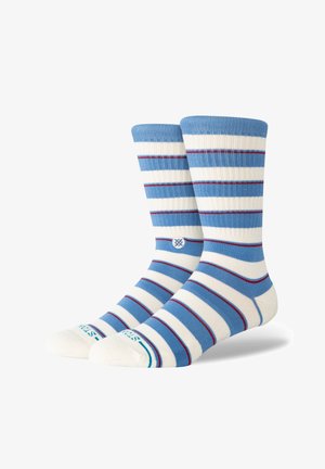 Paire de chaussettes mi-mollet à rayures horizontales bleues, blanches et fines rouges, avec un petit logo circulaire près de la cheville.