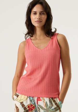 Haut rose sans manches avec un col en V, présentant un motif en maille texturée. Assorti à un pantalon coloré à motifs aux inspirations naturelles.