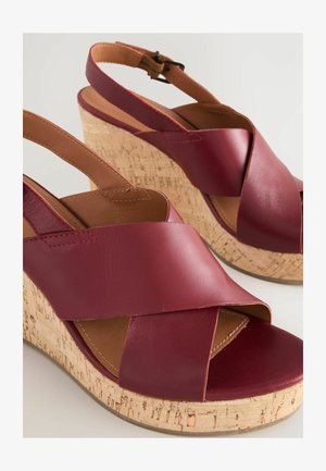 Kastanienbraune Leder-Wedgesandalen mit überkreuzten Riemen und einer Korkplattform. Verfügt über einen verstellbaren Knöchelriemen und eine strukturierte Laufsohle.