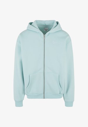 Gaiši zils rāvējslēdzēja džemperis ar kapuci, izgatavots no mīksta materiāla, ar kangaru kabatu, ribotām aprocēm un nelielu baltu logo uz krūtīm.