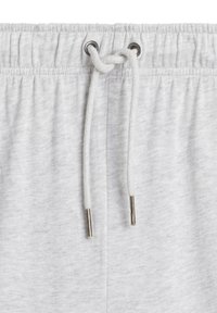 Jasnoszare dresy mają elastyczny pas ze sznurkiem, w tym metalowe końcówki. Materiał ma miękkie, teksturowane wykończenie.