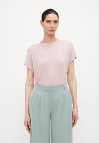 Blusa de rayas rosa claro con escote redondo y mangas cortas, combinada con pantalones de pierna ancha en color verde menta. Textura de tela suave.