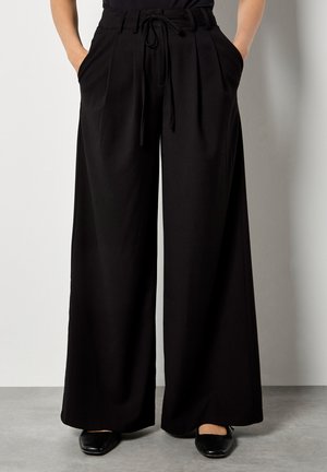 Weite schwarze Hosen mit hoher Taille, gefältelter Vorderseite und Kordelzug. Mit seitlichen Taschen und einer glatten Stofftextur.