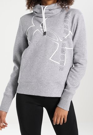 Vrouw draagt een grijze Under Armour hoodie met wit logo en trekkoorden, gecombineerd met zwarte sportleggings.