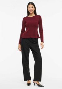 Bordo värvi soonikkoes pika varrukaga pluus pepitallaga, kombineeritud mustade sirgete pükstega ja mustade teravate ninaosaga kontsakingadega.