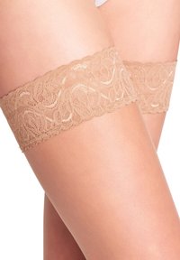 Calze autoreggenti beige in pizzo con un motivo floreale sulla parte superiore, caratterizzate da una texture morbida e liscia e da una vestibilità aderente attorno alle cosce.