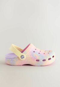 Clog z vzorom tie-dye z rumeno trakom in gumbom nasmejančkom, ki ima ventilacijske luknje, izdelan iz lahkega plastike, v pastelnih barvah.