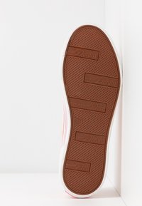 Semelle en caoutchouc marron avec une texture à motif, bordure blanche et détails de marque, présentant un design rayé rose clair et orange sur le c ôté.