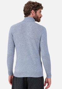 Hellblauer Strickpullover mit hohem Kragen, enganliegenden Ärmeln und geripptem Saum. Weiche Textur, nahtloses Design und mittlere Dicke.
