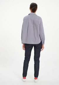 Chemise à rayures à manches longues avec une coupe décontractée, fabriquée en tissu léger, associée à un jean en denim noir et des baskets blanches.