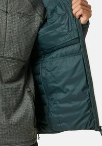Giacca grigia con texture e interno verde, dotata di chiusura con zip, tasche laterali e un logo nella parte superiore sinistra.