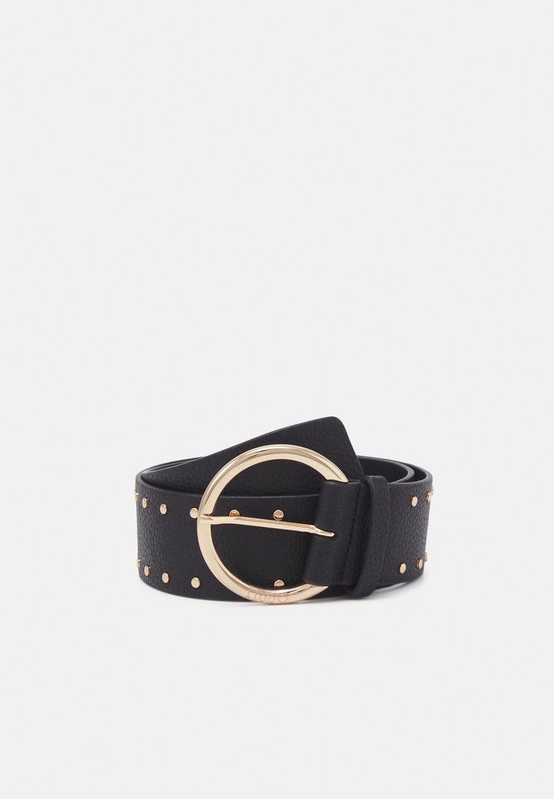 Ceinture en cuir noir avec petits clous dorés et grande boucle ronde dorée, roulée sur fond blanc.