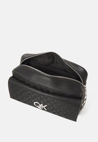 Borsa nera realizzata con materiali misti. Presenta un corpo strutturato, una parte superiore liscia, hardware in acciaio inossidabile e una chiusura a zip con interno brandizzato.