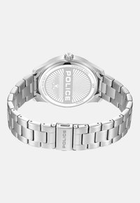 Reloj de acero inoxidable con un acabado pulido. Presenta una caja redonda, una pulsera de eslabones y una parte trasera grabada que muestra "POLICE" y un diseño de estallido solar.