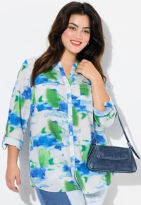 Camicia leggera a maniche lunghe con motivo acquerello blu e verde; due tasche frontali; abbinata a una piccola borsa in denim.