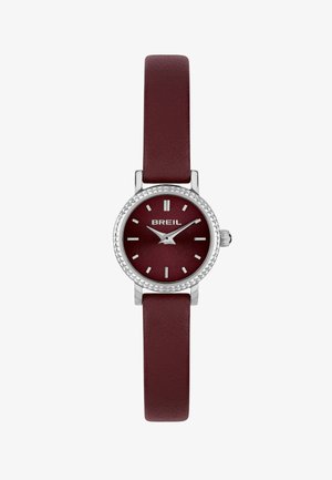 Bordeaux leren strap horloge met een ronde kast van zilverkleurig roestvrij staal, een gestructureerde bezel en een bijpassende bordeaux wijzerplaat, voorzien van zilveren uurmarkeringen.