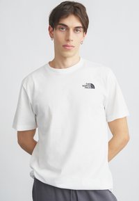 Λευκό βαμβακερό t-shirt με στρογγυλή λαιμόκοψη και κοντά μανίκια, με ένα μικρό μαύρο λογότυπο στο αριστερό στήθος. Μαλακή υφή και άνετη εφαρμογή.