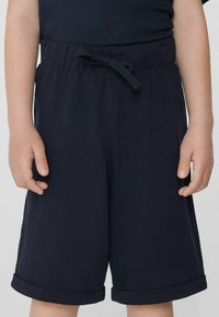 Shorts bleu marine en tissu texturé, avec une taille élastique et un cordon de serrage. Caractérisés par des ourlets retournés et une coupe décontractée.