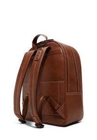 Mochila de piel marrón con una textura suave, cierre de doble cremallera, correas ajustables y un bolsillo frontal vertical.