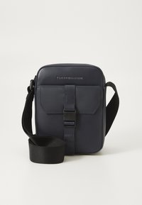 Navy leather shoulder bag with a rectangular shape, adjustable strap, front flap, and logo detailing above the flap. Smooth texture.