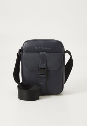 Marine leren schoudertas met een rechthoekige vorm, verstelbare schouderband, voorflap en logo-details boven de flap. Gladde textuur.