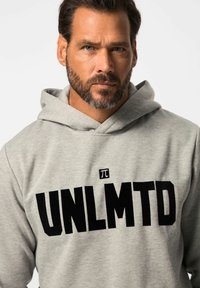 Sudadera gris hecha de un tejido suave que presenta un gran logo negro "UNLMTD" con un pequeño símbolo de π encima. El diseño incluye una capucha con cordón.