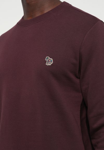 Maroon long-sleeve crewneck sweatshirt featuring a small multicolored embroidered horse logo on the chest. Smooth cotton fabric.