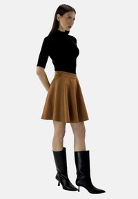 Top negro de manga corta, falda marrón en línea A hecha de tejido suave, botas de cuero negro hasta la rodilla, textura suave, diseño minimalista.