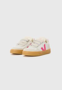 Hvite og lysegrå sneakers med rosa detaljer og en teksturert gummisåle. Har borrelåsstropper og perforerte detaljer på tåen.