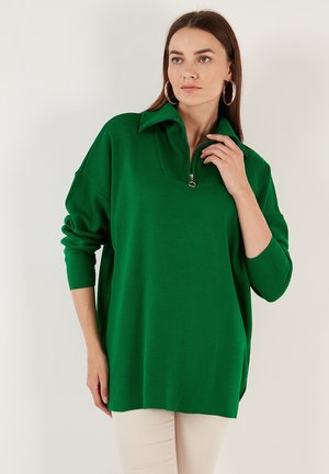 Green knit pullover with a high collar and half-zip closure. Features loose fit and long sleeves, made from a soft, textured fabric.