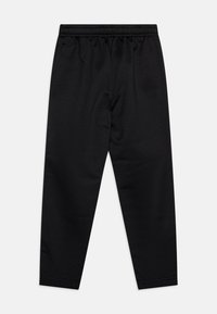 Black athletic pants feature a lightweight, textured material, elastic waistband, and tapered legs. Small brand logo on the left hip.