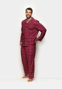 Karierter Pyjama-Set in Rot, Blau und Schwarz. Das Langarmhemd verfügt über eine Tasche, und die Hose hat einen elastischen Bund. Weicher Stoff.