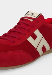 Baskets en daim et tissu rouge avec lacets rouges, logo latéral blanc et étiquette beige portant la marque Elisabetta Franchi.