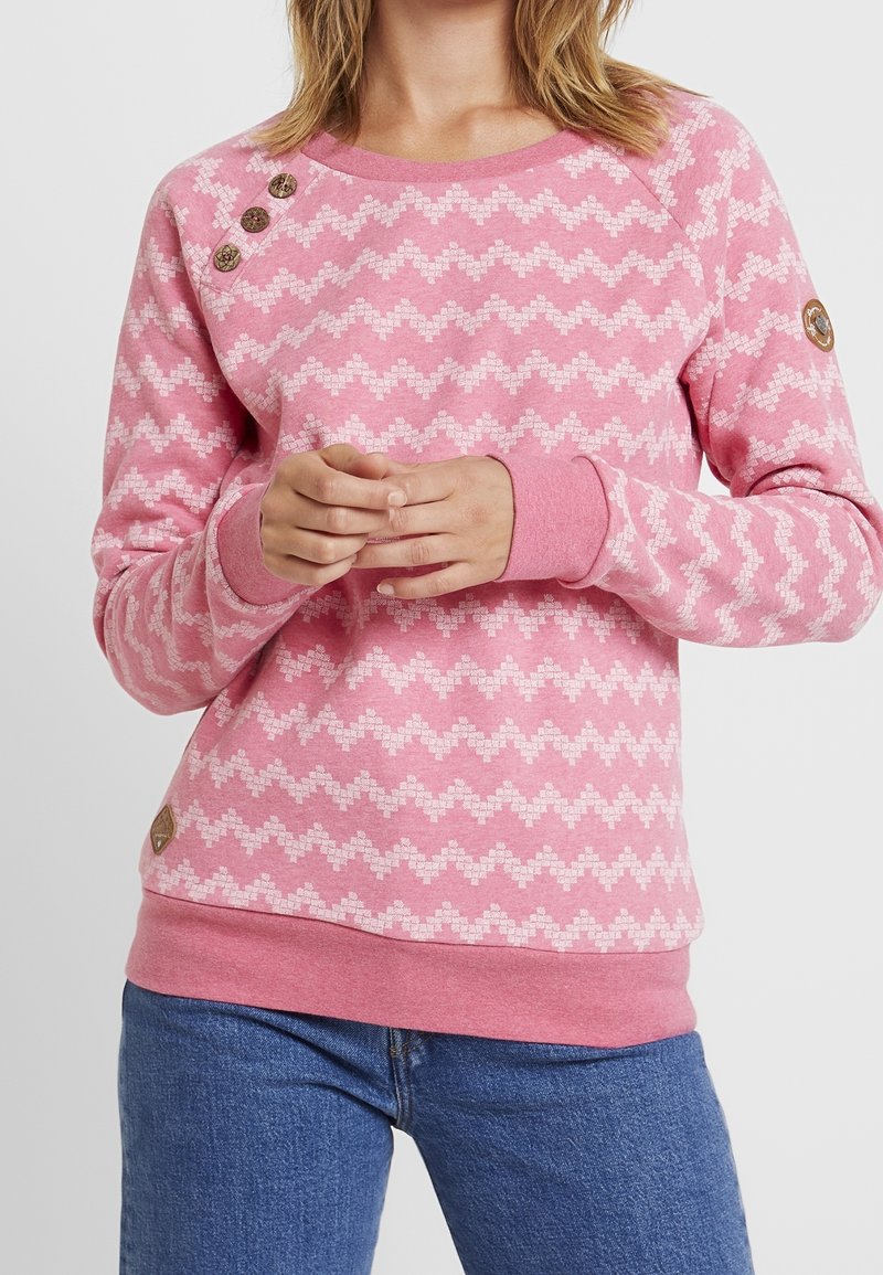 Felpa rosa con motivo a zigzag in una tonalità di rosa più chiara, polsini a coste e bottoni decorativi sulla spalla. Realizzata in tessuto morbido.