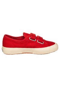 Baskets en toile rouge avec deux bandes Velcro, bout rond, semelle en caoutchouc et tissu texturé avec un design superposé.
