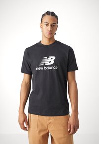 Black cotton t-shirt featuring a white "New Balance" logo on the chest. Classic fit with short sleeves and a round neckline.