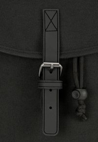 Fekete textúrájú táska lapos csat pánttal, fém kiegészítőkkel és zsinóros záródással a biztonságos rögzítés érdekében.