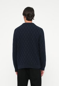 Námornícky pletený cardigan s textúrovaným vzorom, okrúhlym výstrihom, dlhými rukávmi a rebrovanými manžetami. Vyrobený z mäkkého, odolného materiálu.