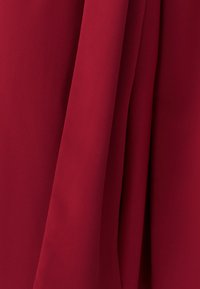 Punane kangas, pehme tekstuuriga, kergelt läikiva pinnaga, sileda väljanägemisega. Omab volditud osi, mis loovad pehmed jooned ja sügavuse.