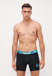 Zwarte boxershorts met een kleurrijke patroon tailleband. Bevat een Nike-logo op het been. Materiaal lijkt rekbaar en aansluitend.